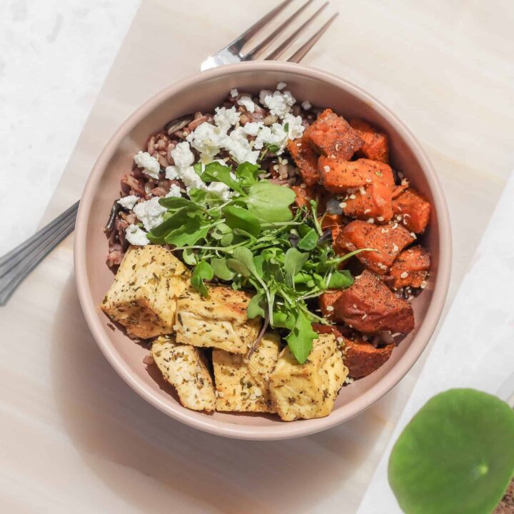A bowl with rice, marinated baked tofu, sweet potato, goat cheese, and microgreens