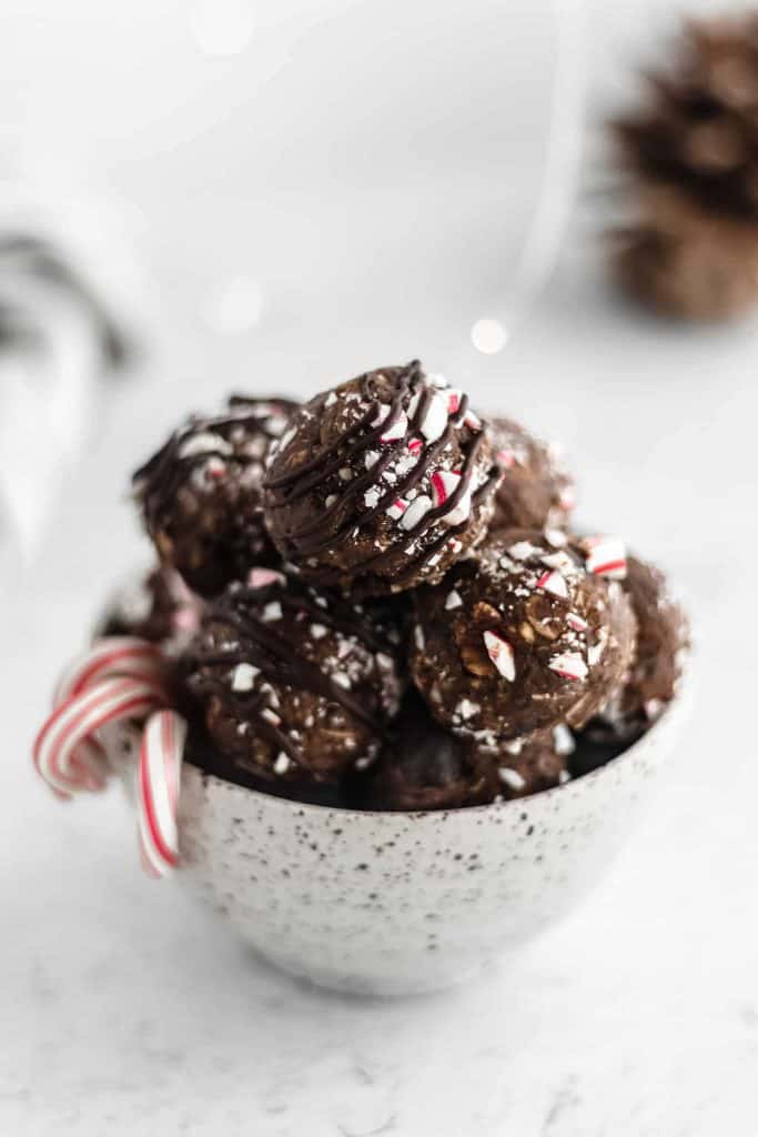 A photo of chocolate peppermint bliss balls in a white bowl with fairy lights in the background