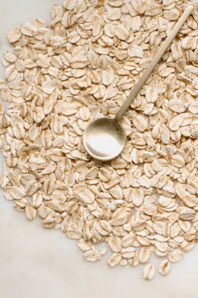 Raw oats with a golden metal spoon on top of them