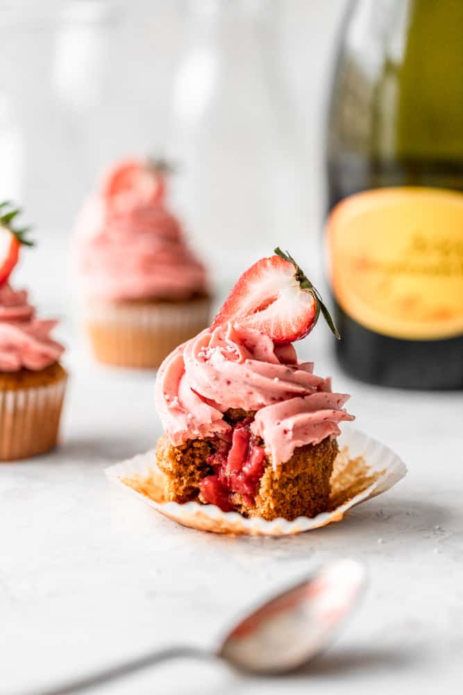 a strawberry prosecco cupcake with a bite taken out of it