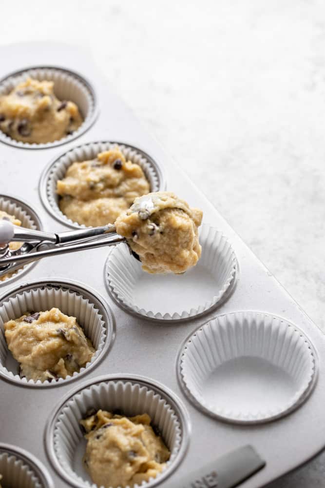 scooping muffin batter into muffin pan