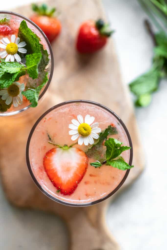 A cocktail topped with a strawberry and small flower.