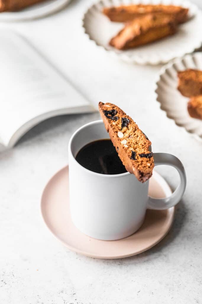A biscotti on the edge of a coffee mug.