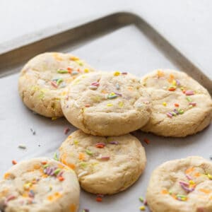 Cookies on a baking sheet with sprinkles on them.