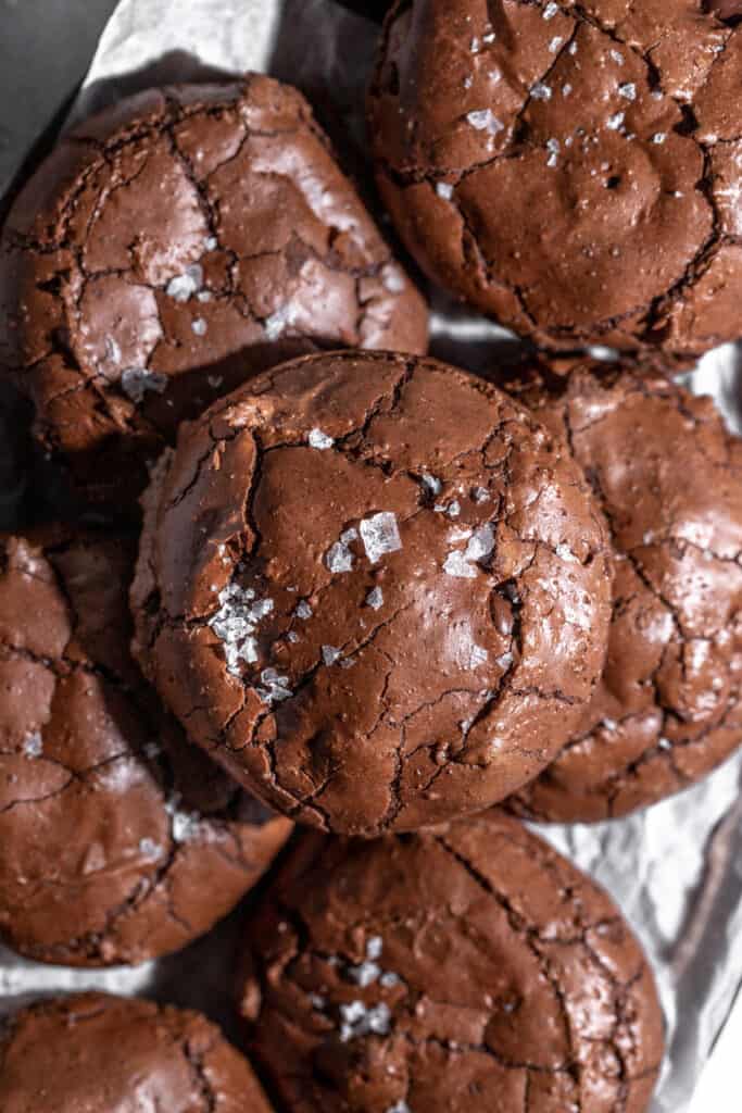 A close up shot of chocolate crinkle cookies with flaky salt on top.