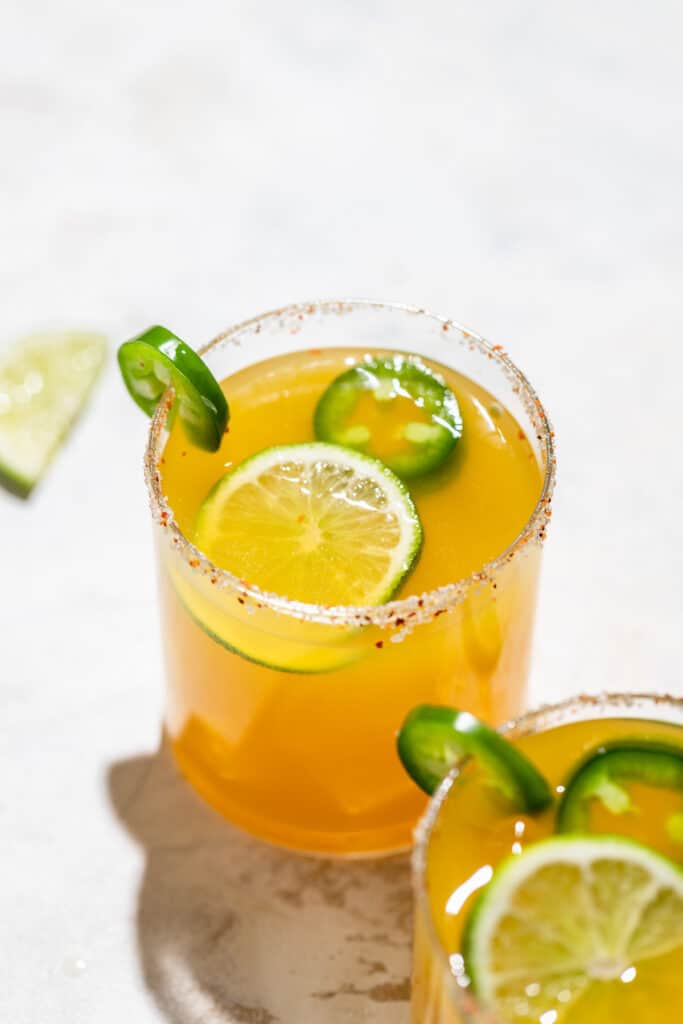 A spicy margarita garnished with jalapeño and lime slices.