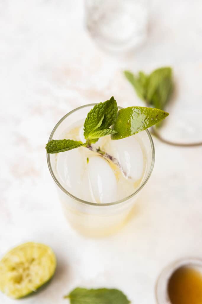 Top down view of a glass of hard seltzer with a mint sprig and lime wedge.