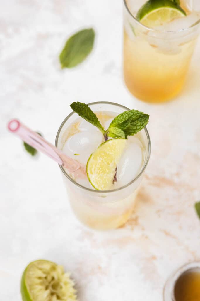 A top down view of a vodka seltzer cocktail with lime, mint leaves, and a pink straw.