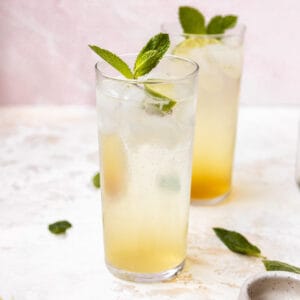 Two cocktails garnished with lime and mint.