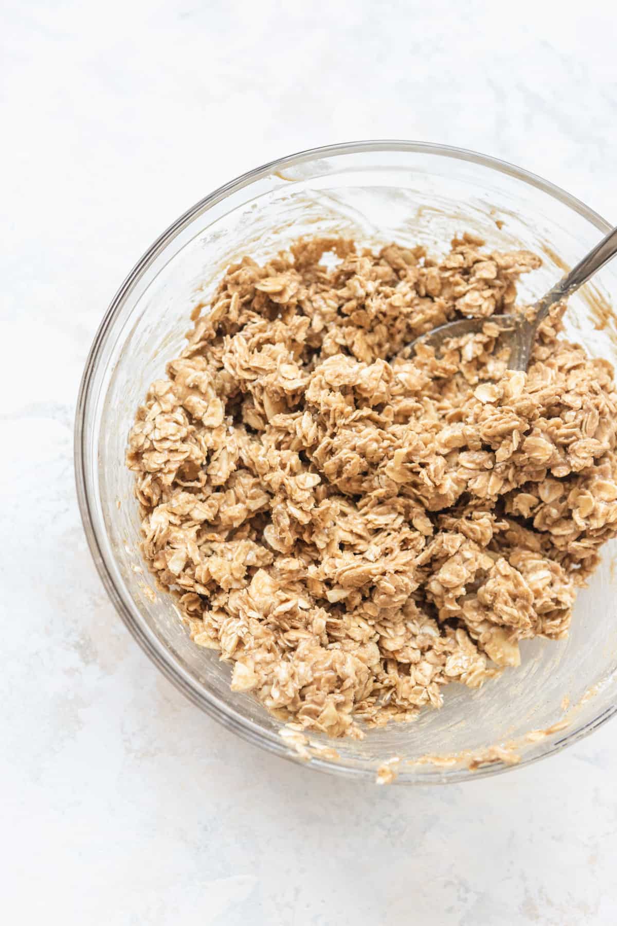 Oats, almonds, almond butter, and honey mixed together in a bowl.