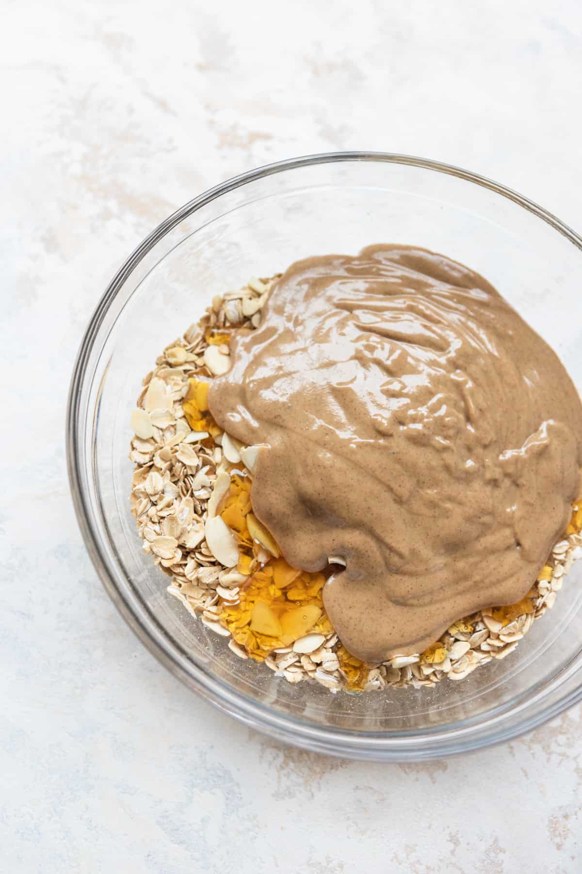 Oats, almonds, honey, and almond butter in a bowl.
