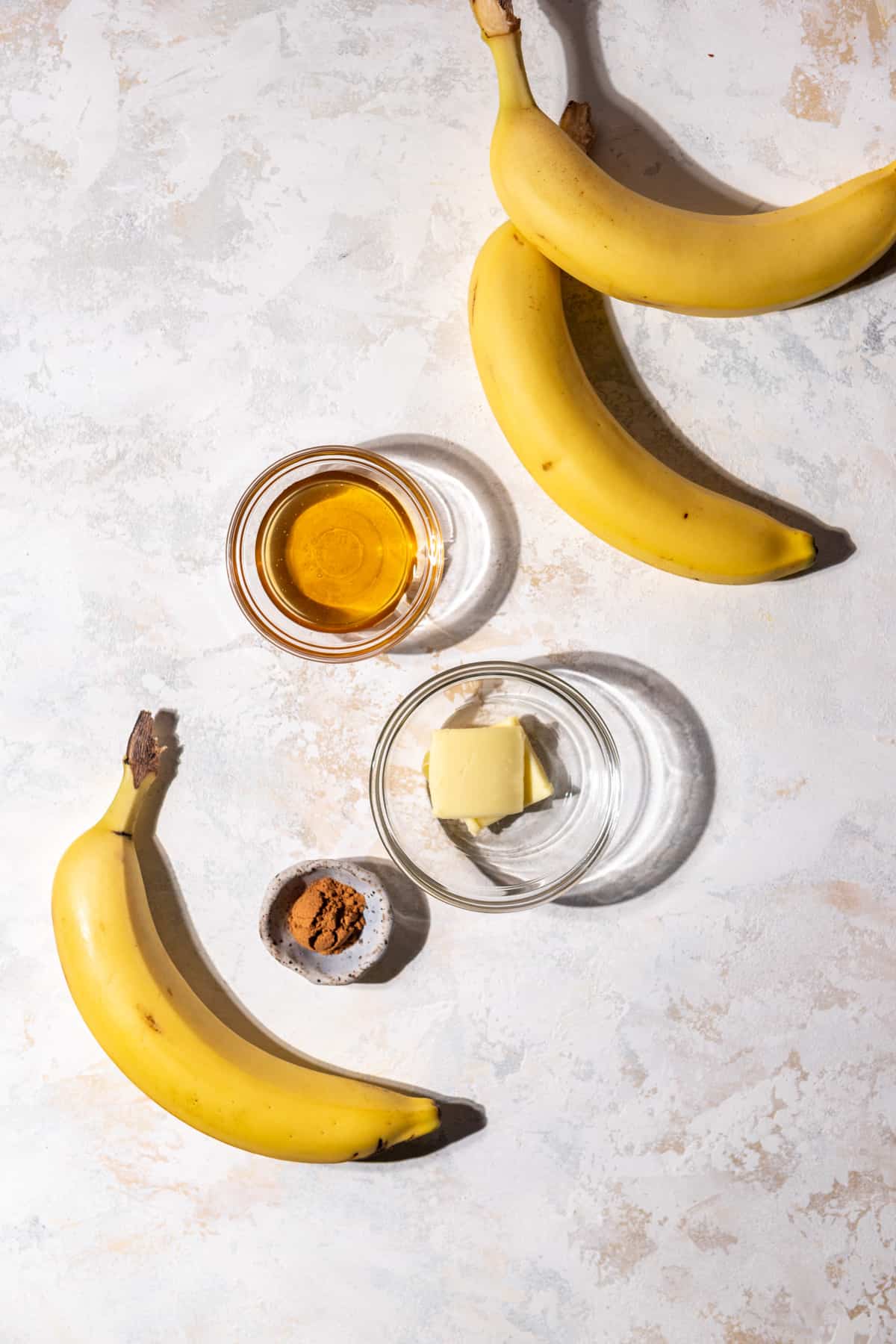 Ingredients to make honey caramelized bananas on a surface.