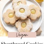 Flower shaped shortbread cookies with lemon curd on a white plate.