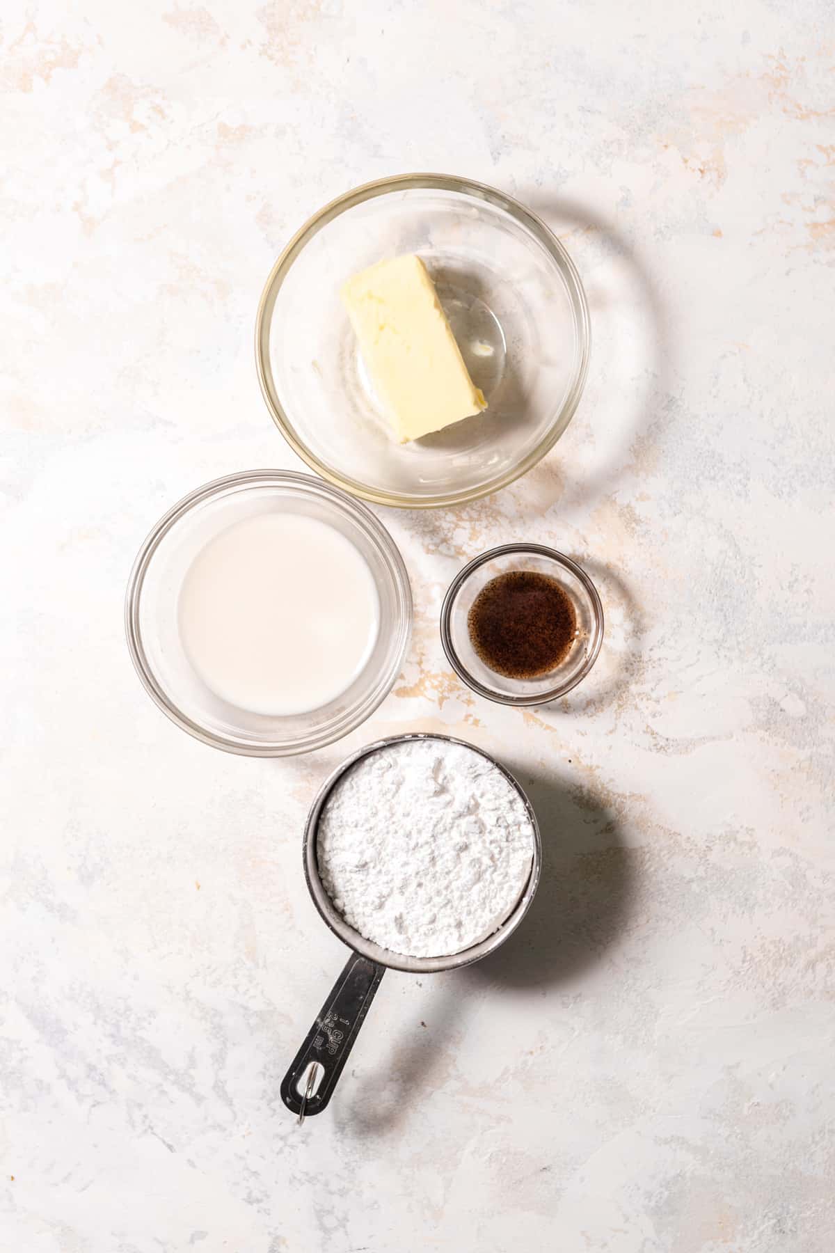 Ingredients to make vanilla buttercream arranged on a surface.