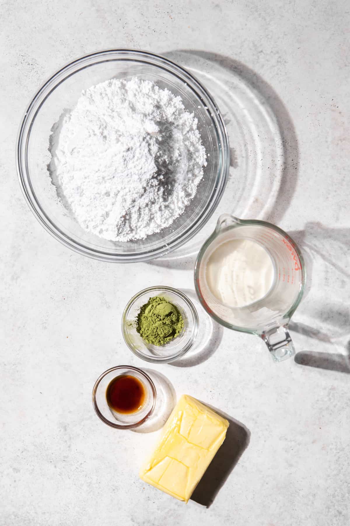 Ingredients to make matcha buttercream on a white surface.