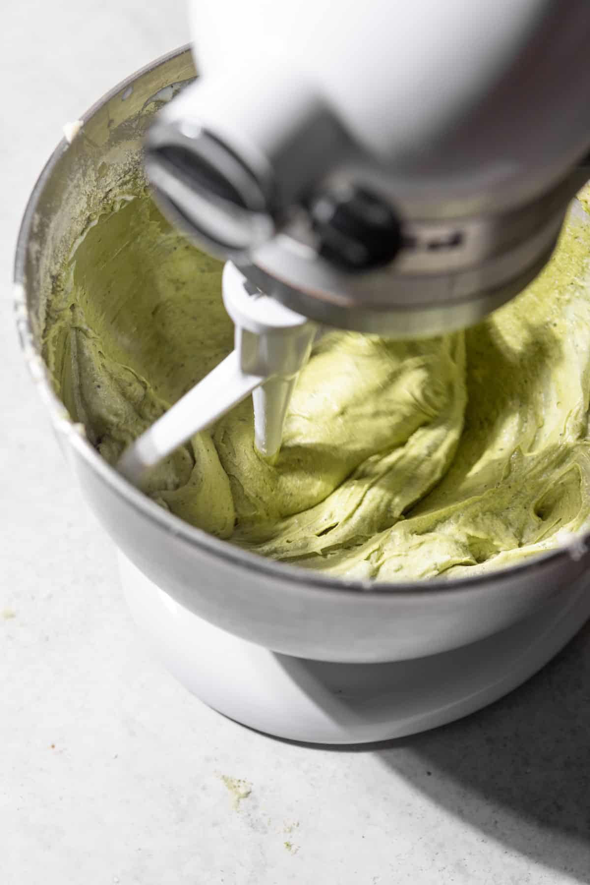 Green cake batter in the bowl of a stand mixer.