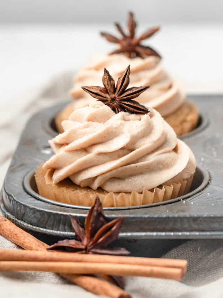 A close up of an apple cider cupcake in a cupcake pan topped with star anise.