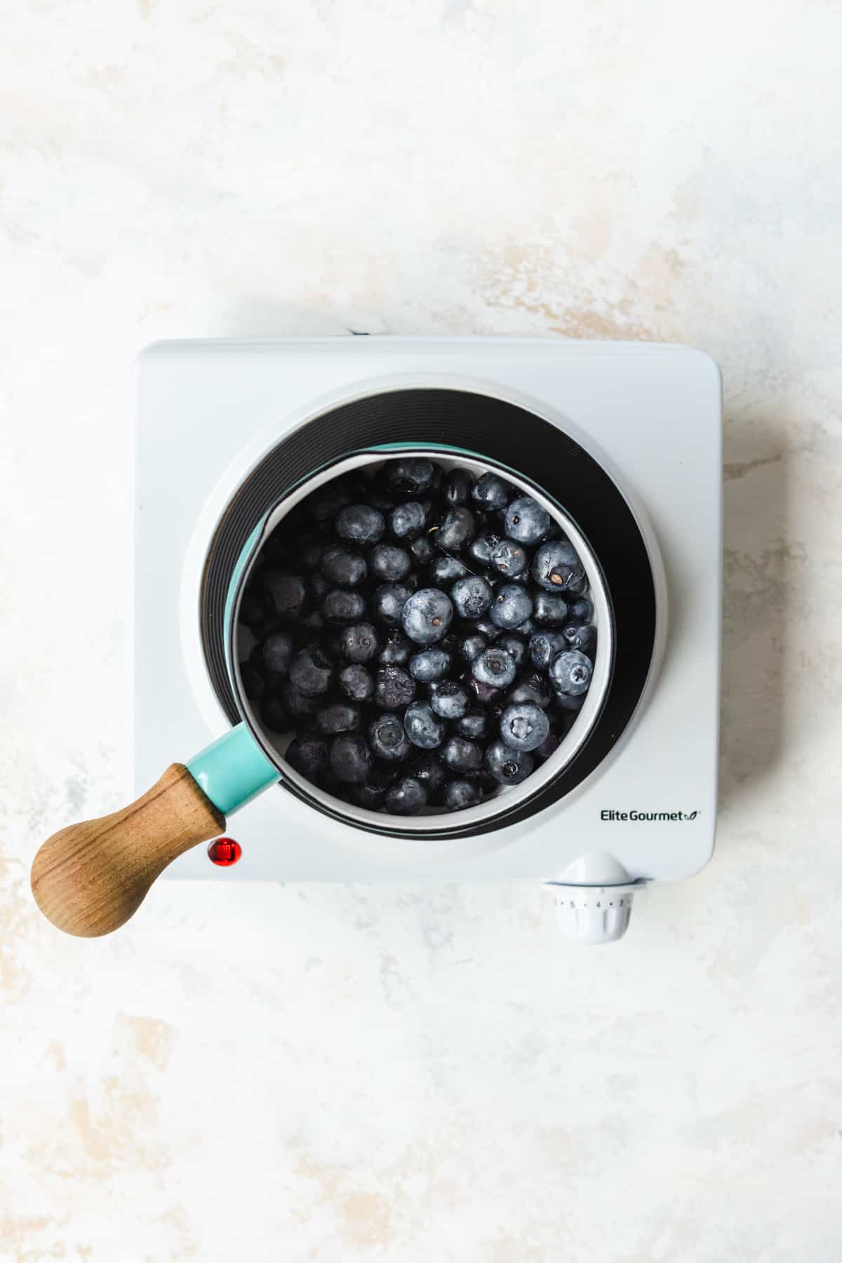 Blueberries in a small pot on a burner.