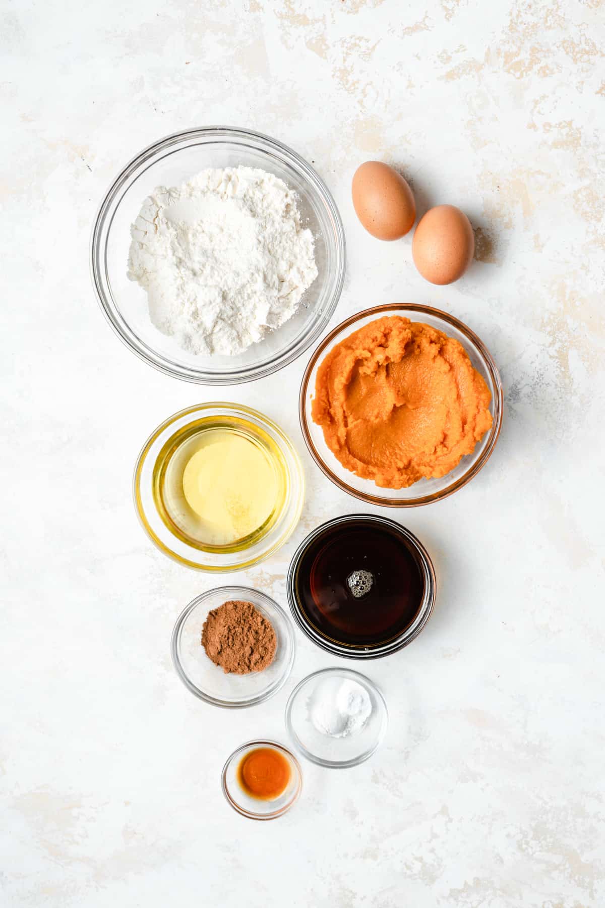 Ingredients to make a pumpkin snack cake on a white surface.