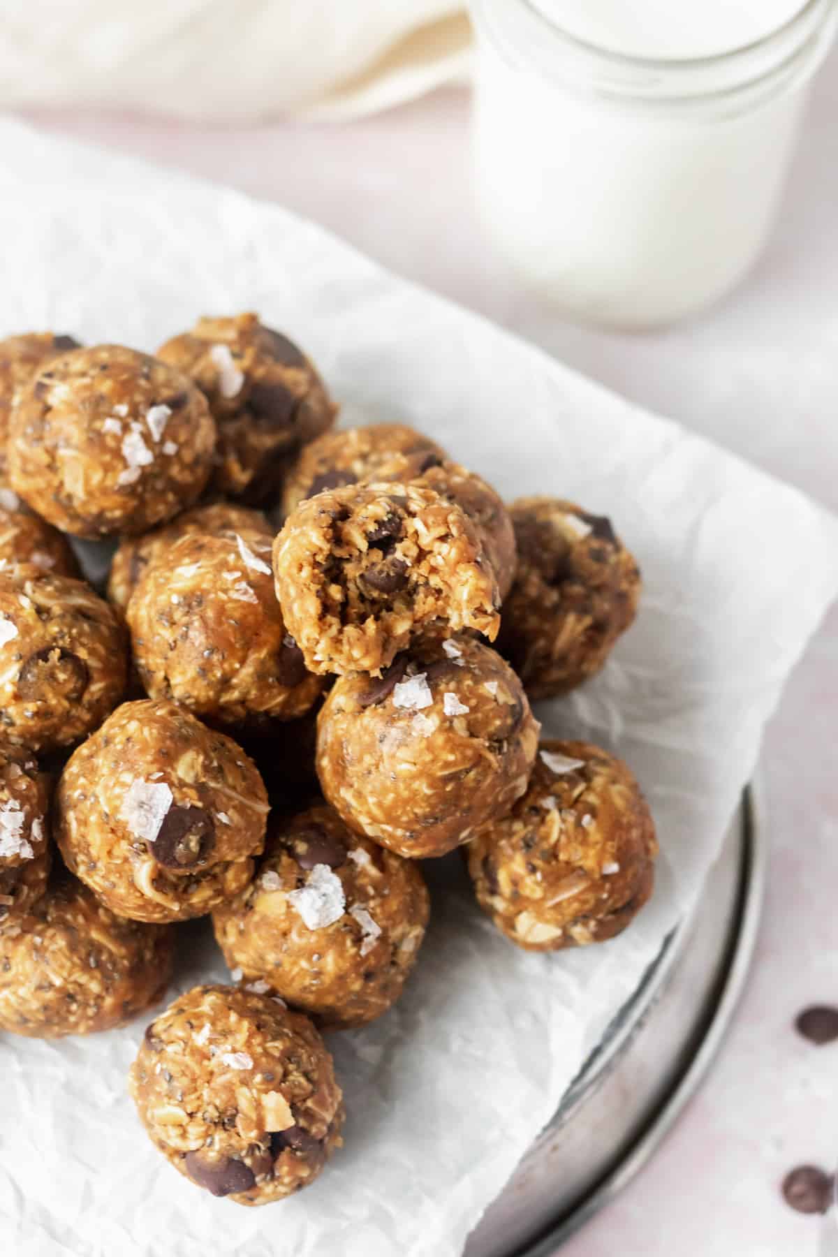 A stack of protein balls on parchment paper. One has a bite taken out of it.
