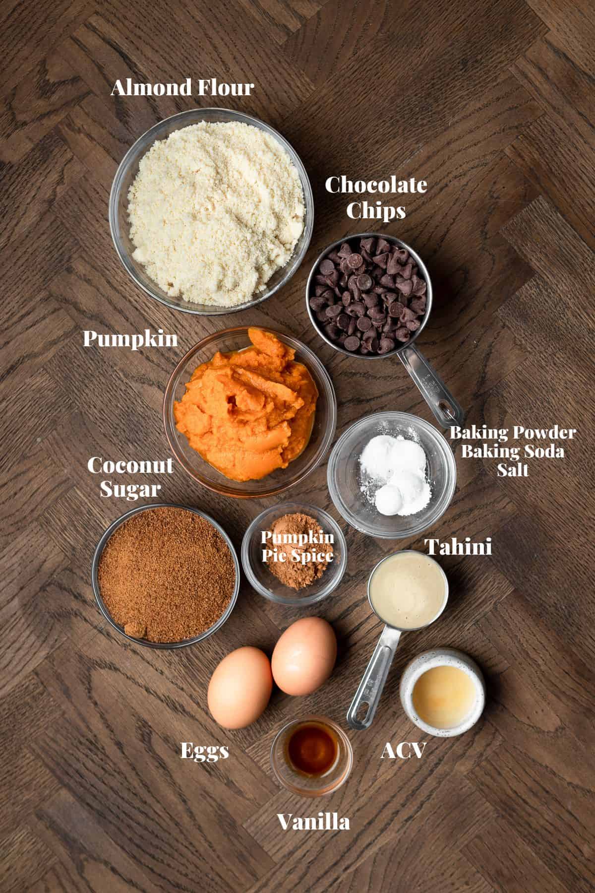 Ingredients to make gluten free pumpkin muffins on a wood surface.