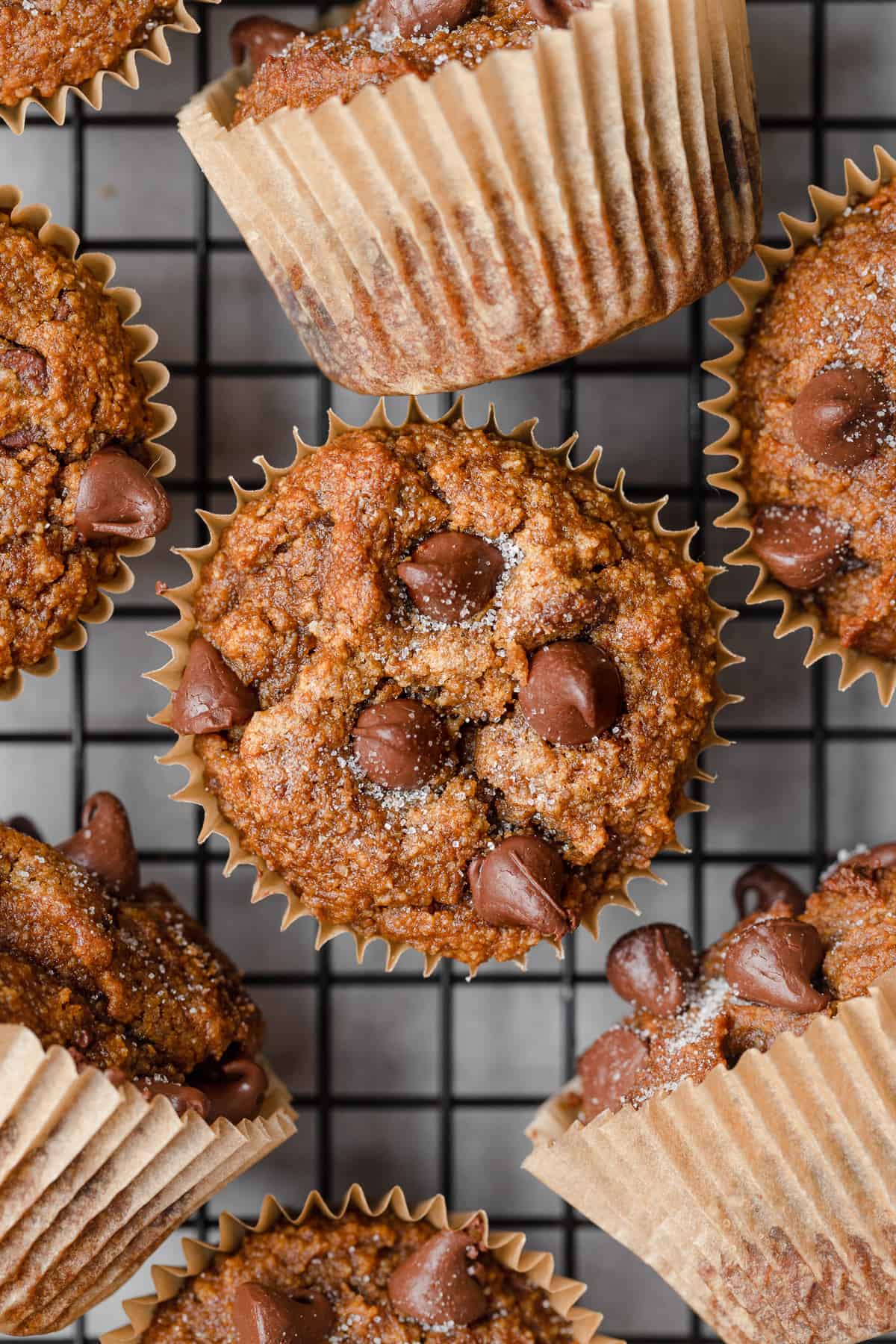 Almond flour pumpkin muffins with chocolate chips on a cooling rack on parchment paper.
