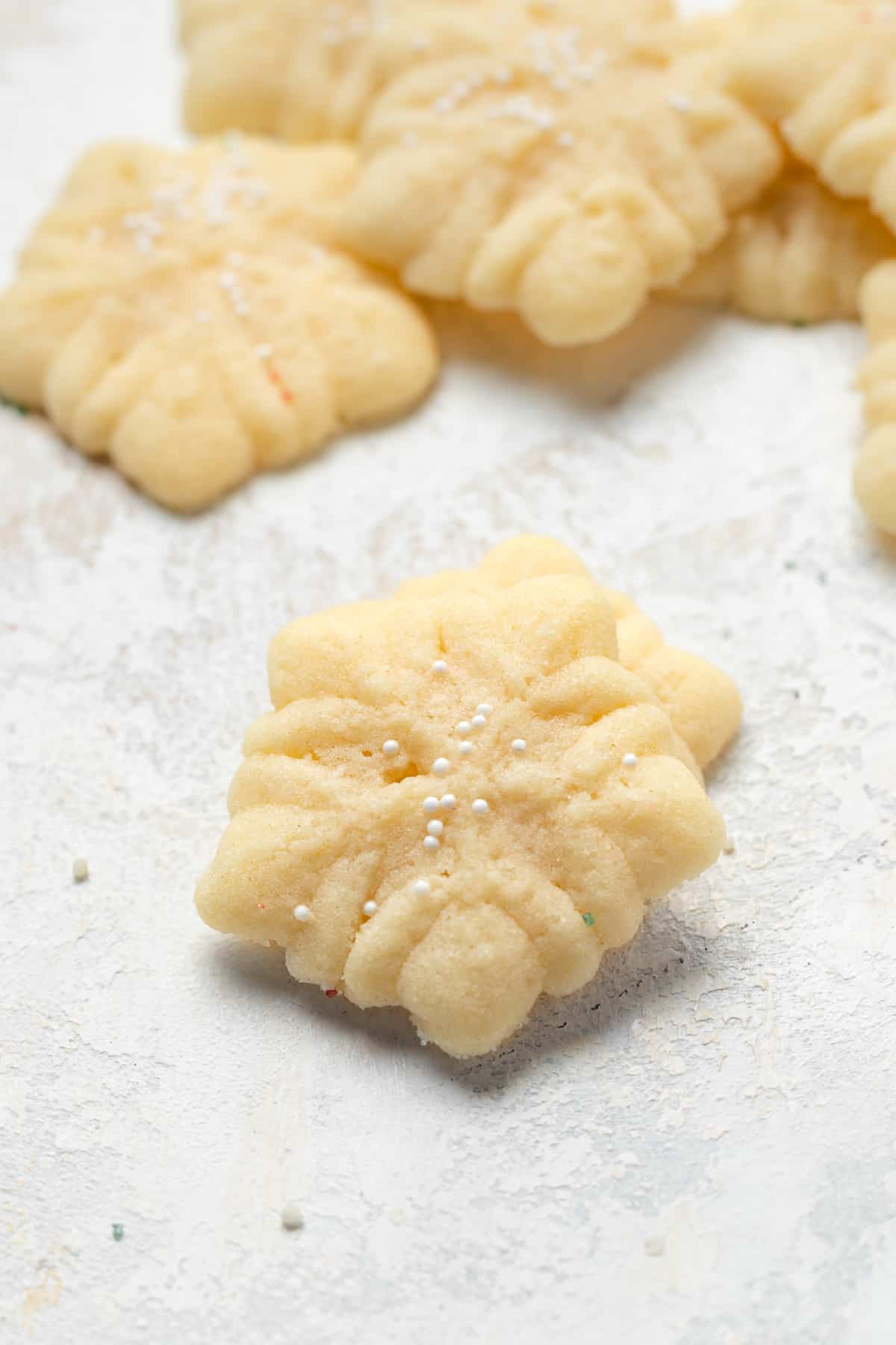 Snowflake shaped spritz cookies with white sprinkles.