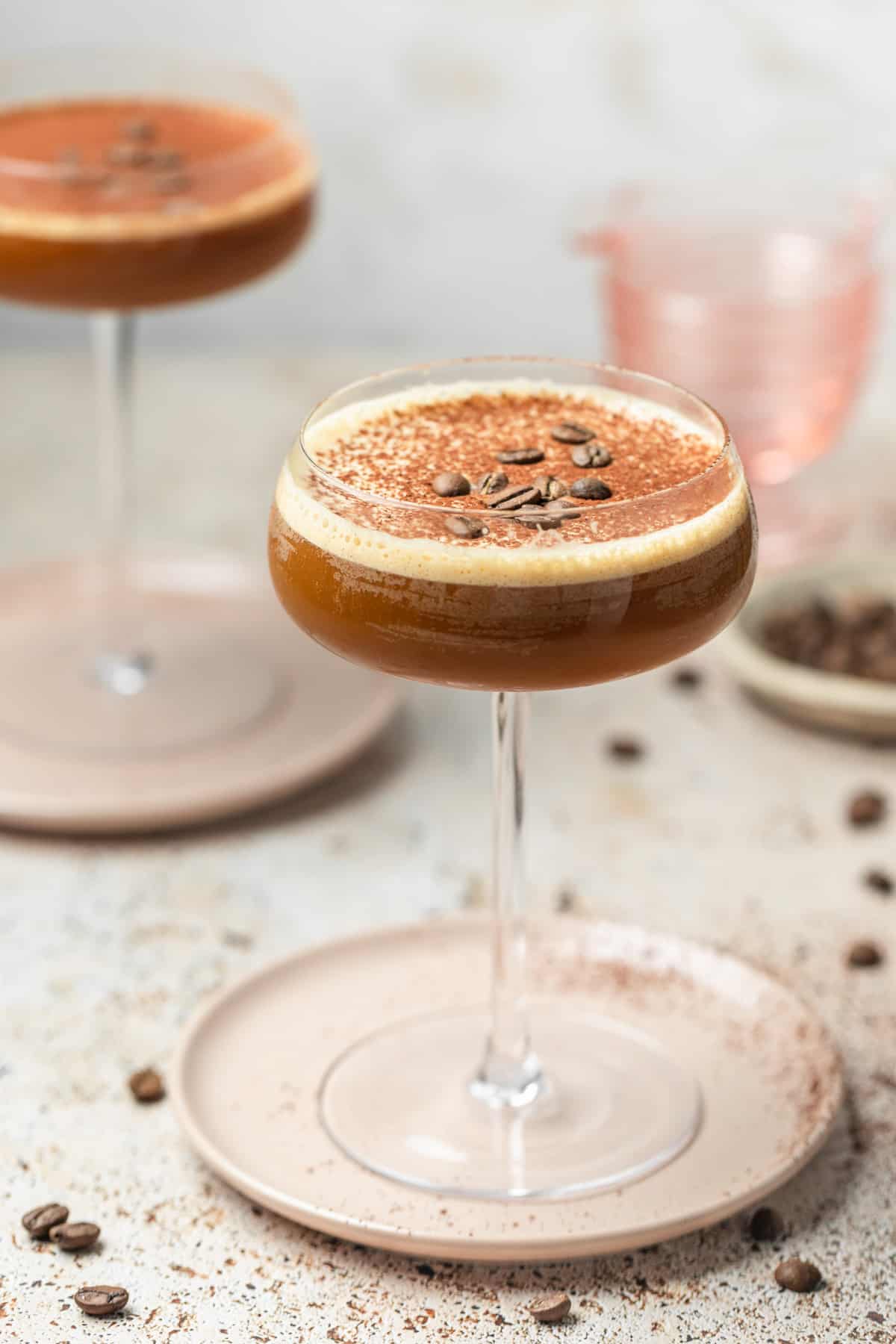 An espresso martini on a pink plate.
