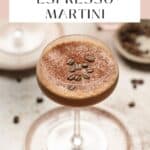 Close up of an espresso martini in a coupe glass on a pink plate.