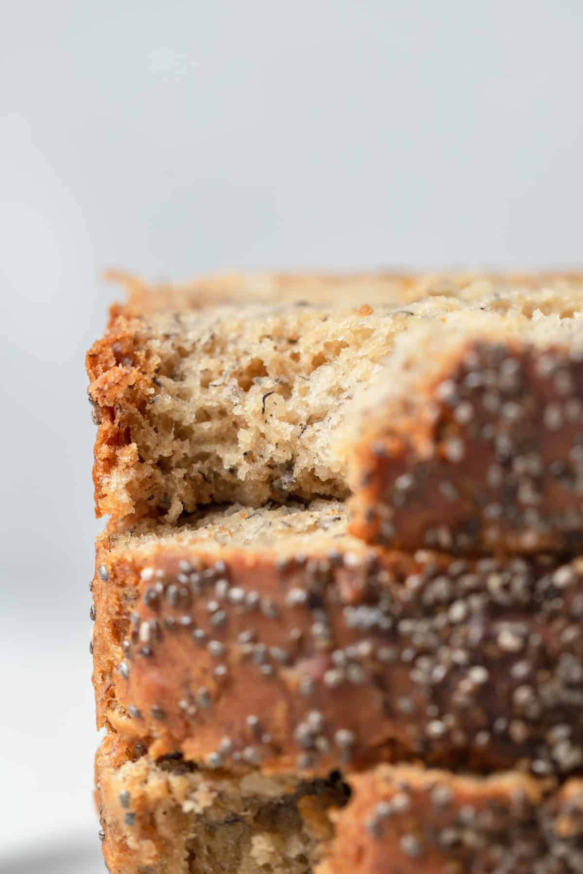 A close up of a slice of banana bread with chia seeds with a bite taken out of it.