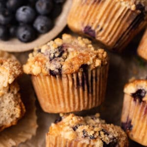 Blueberry muffins stacked on parchment paper.