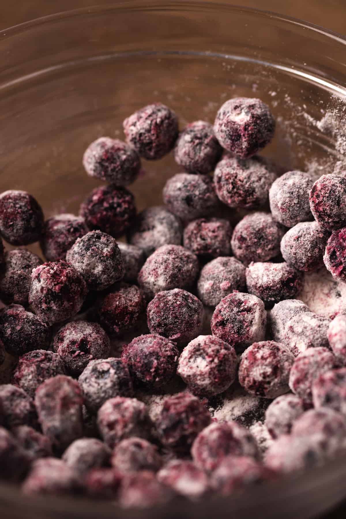 Blueberries coated in flour in a glass bowl.