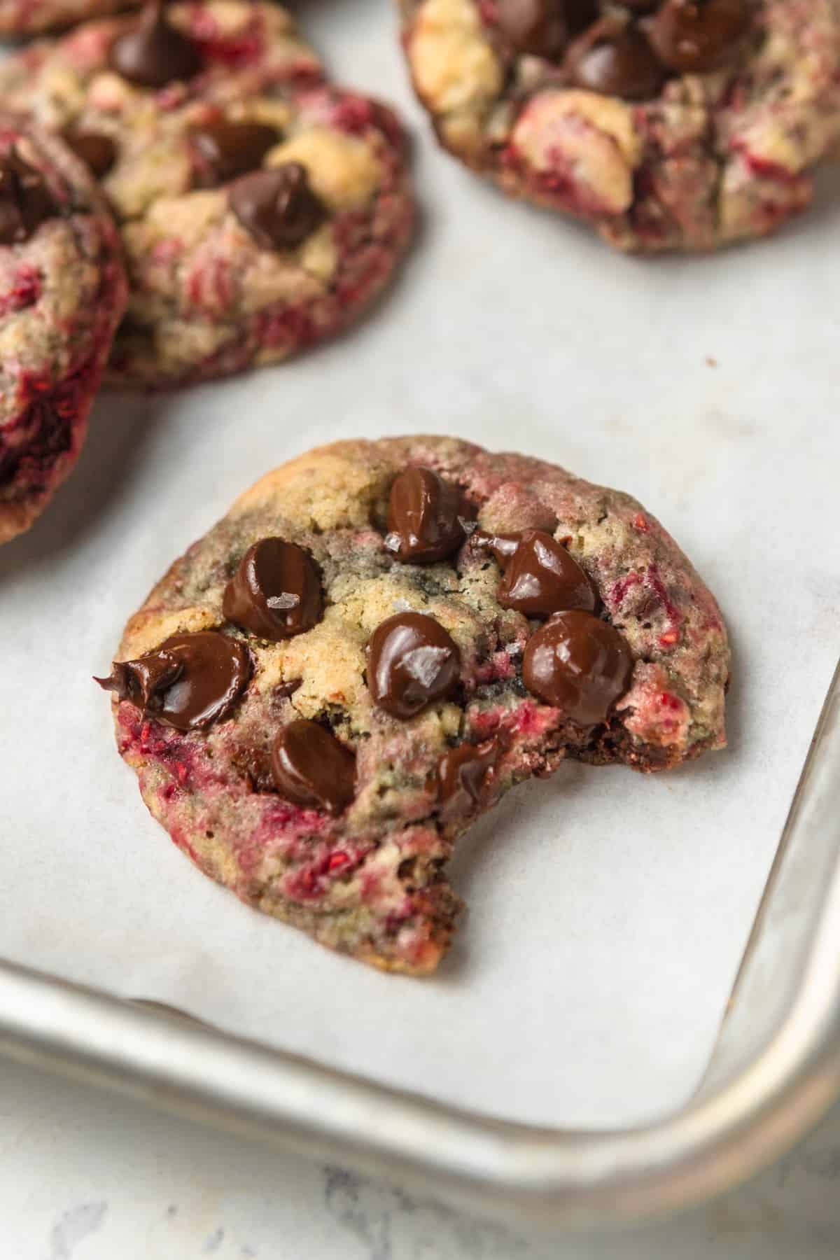 A raspberry chocolate chip cookie with a bite taken out of it.
