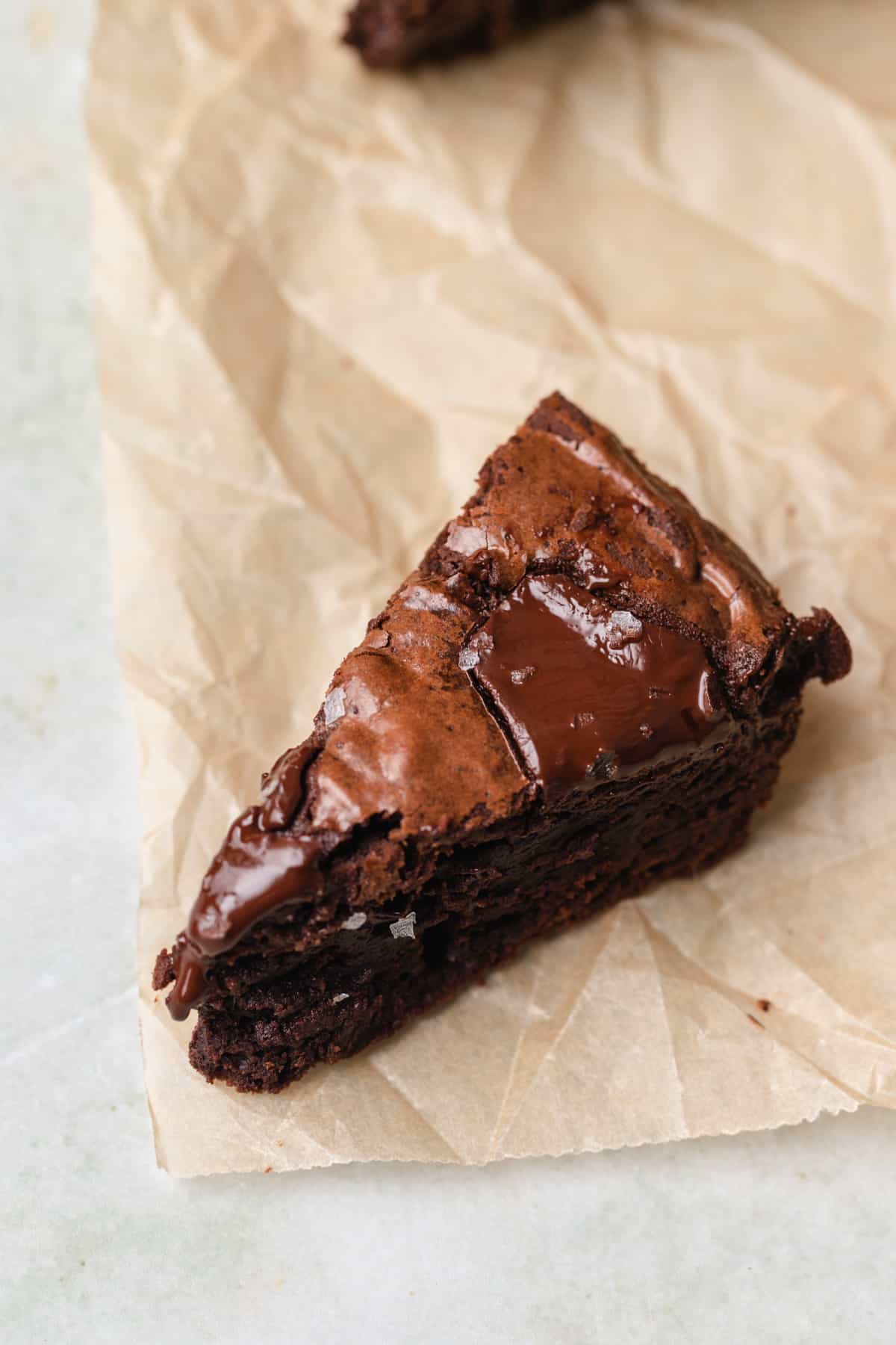 A brownie slice on tan parchment paper.