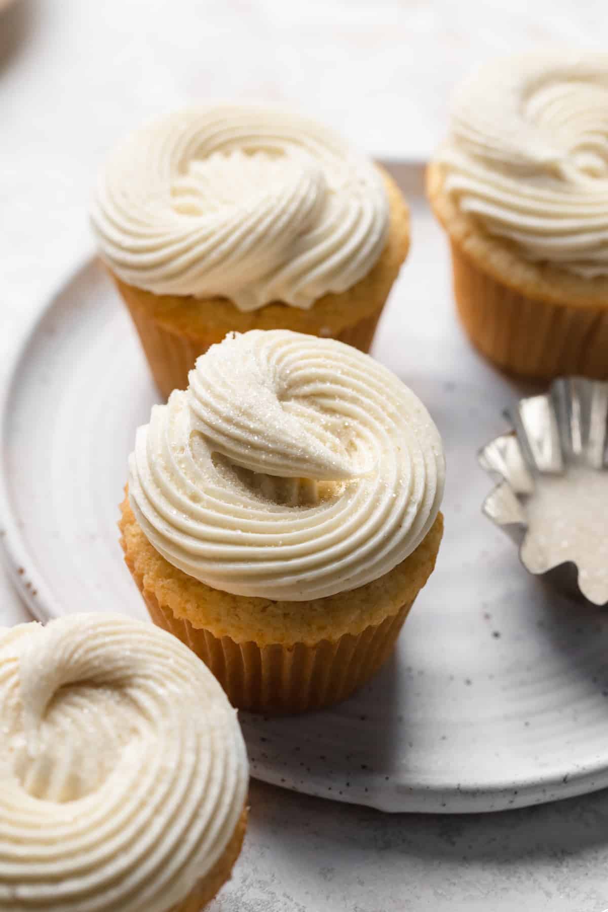 A small batch of 6 vanilla cupcakes on a plate.