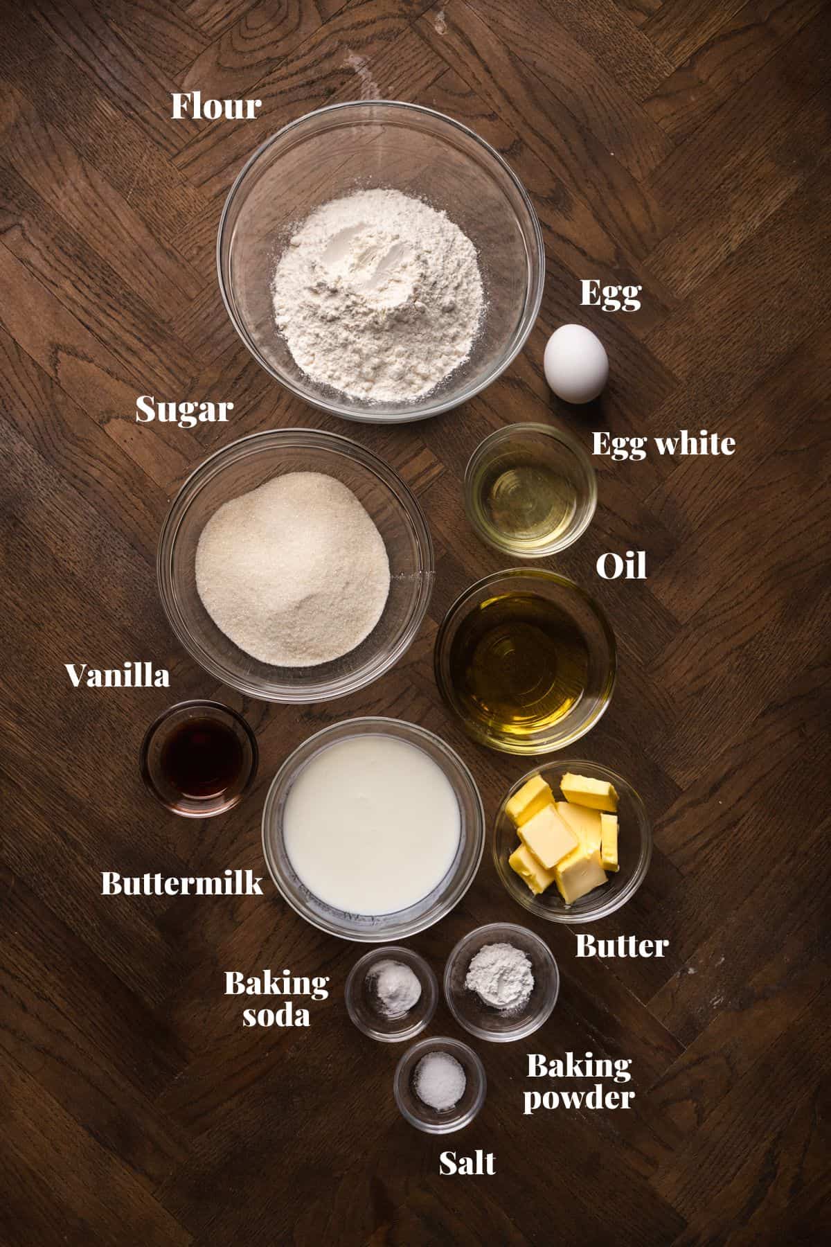 Ingredients to make vanilla cake on a wood background.