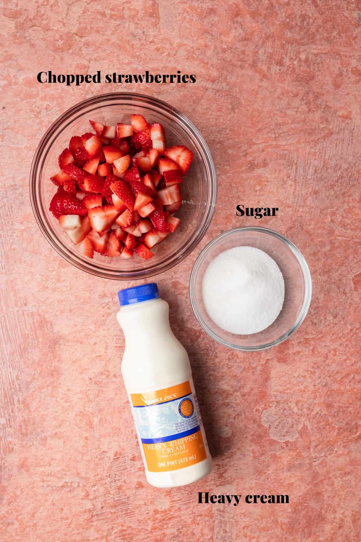 Ingredients to make strawberry mousse on a red surface.