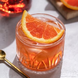 A cocktail topped with a large orange slice.