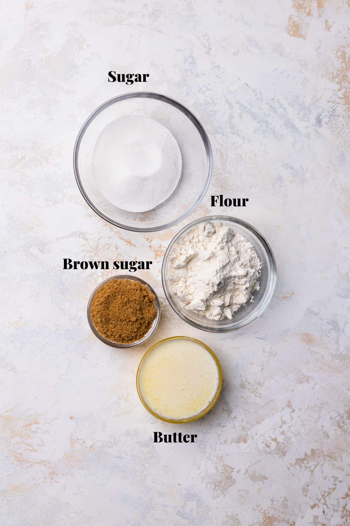 Ingredients to make a crumble topping on a white and pink surface.