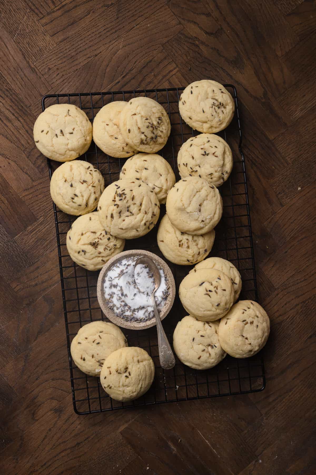 Sugar cookies on a wire rack with a bowl of sugar.
