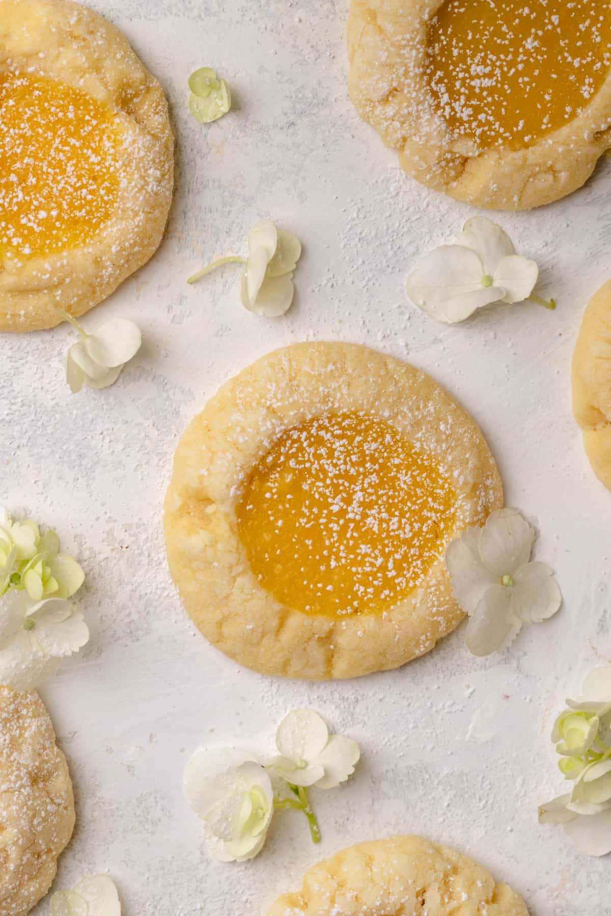 Lemon bar cookies on a white surface with flowers.