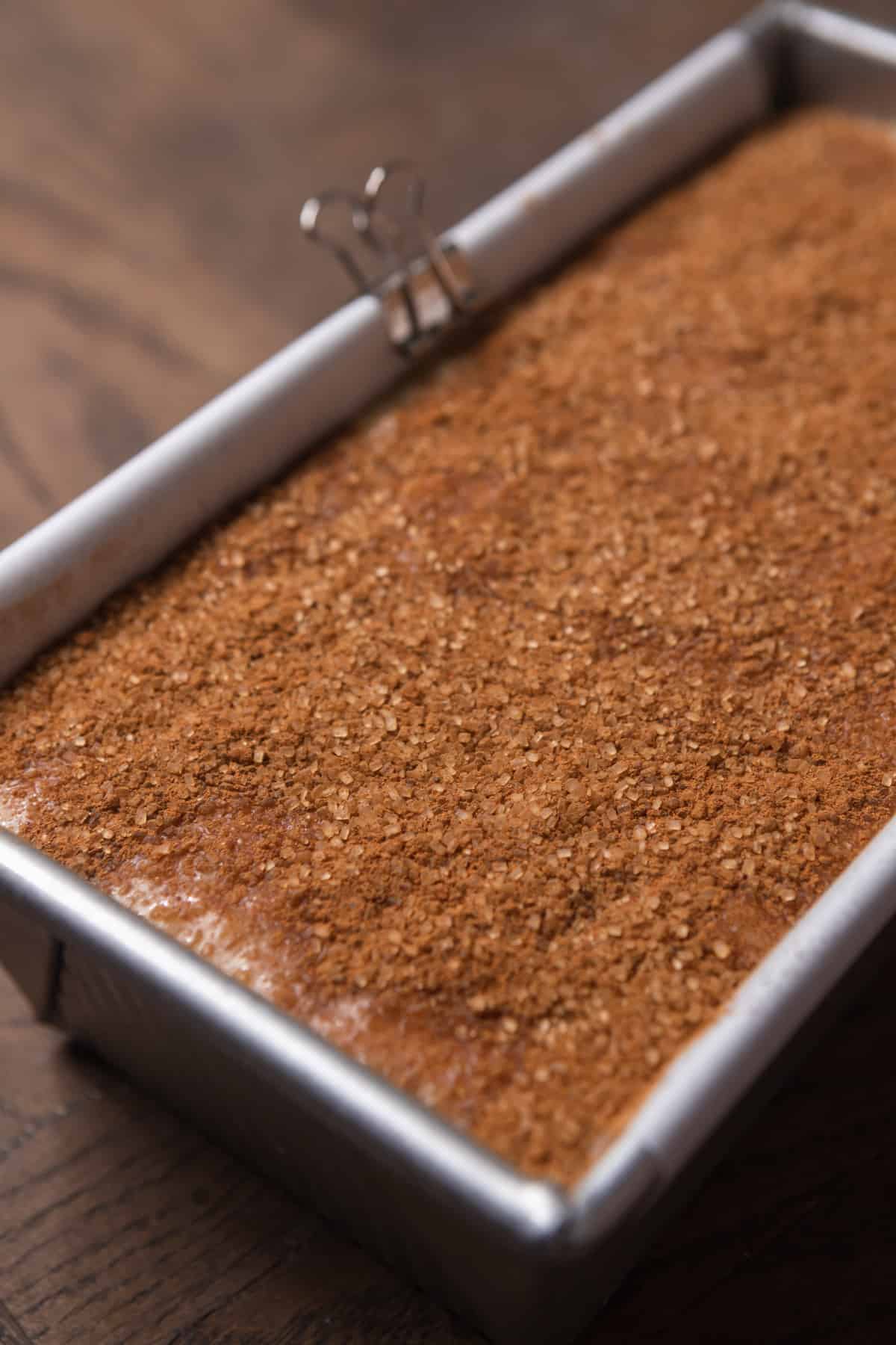 Banana bread batter in a bread pan with a sugar topping.