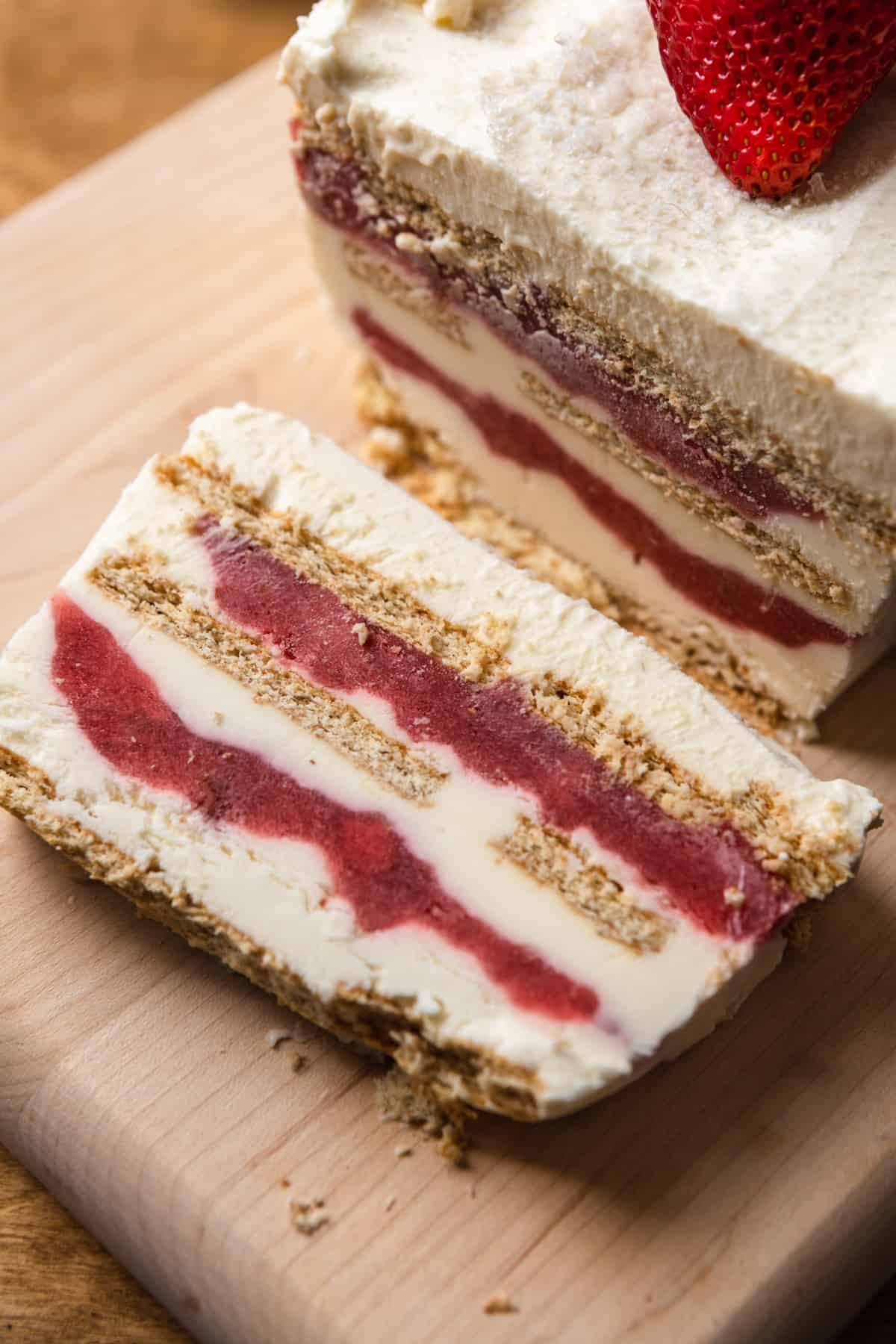 Strawberry cream cheese icebox cake sliced on a wood serving board.