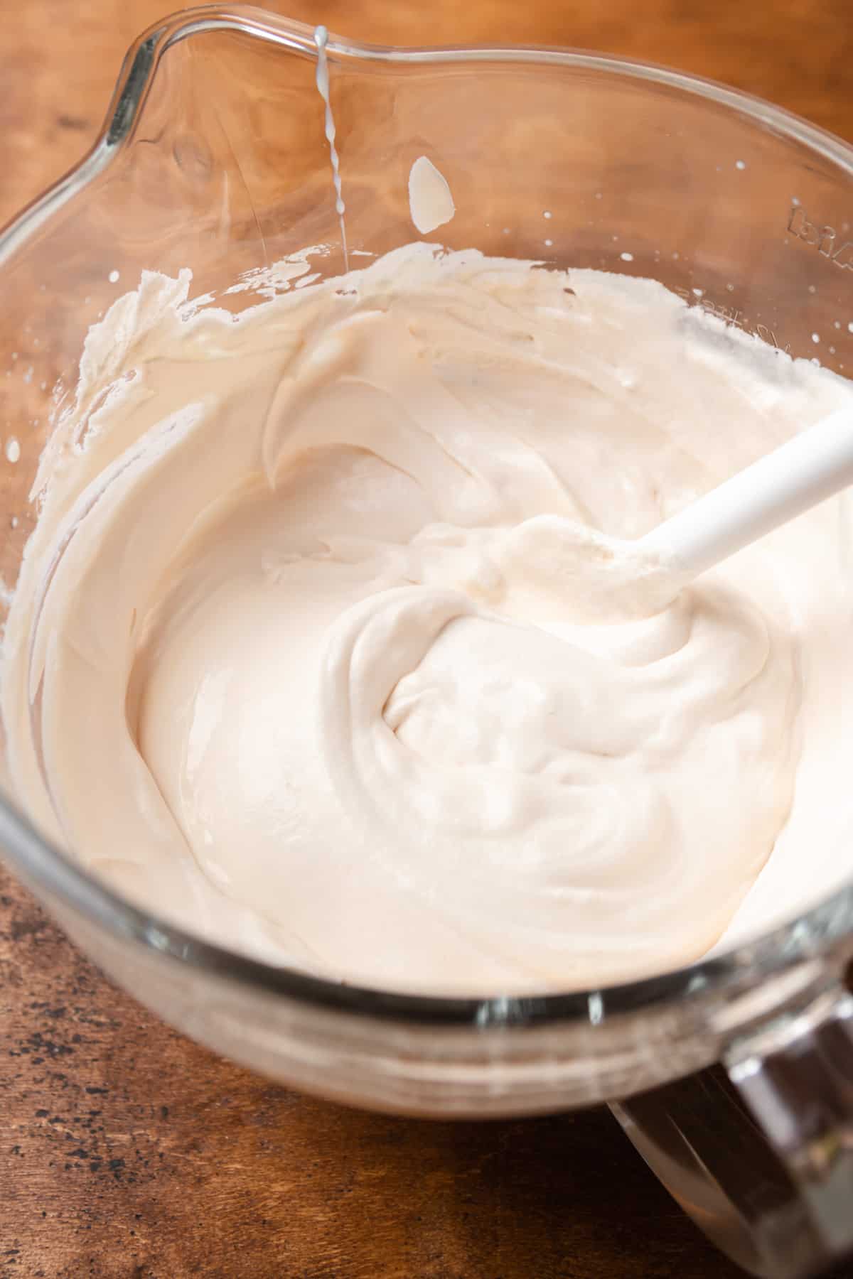 Whipped heavy cream with sweetened condensed milk in a bowl.