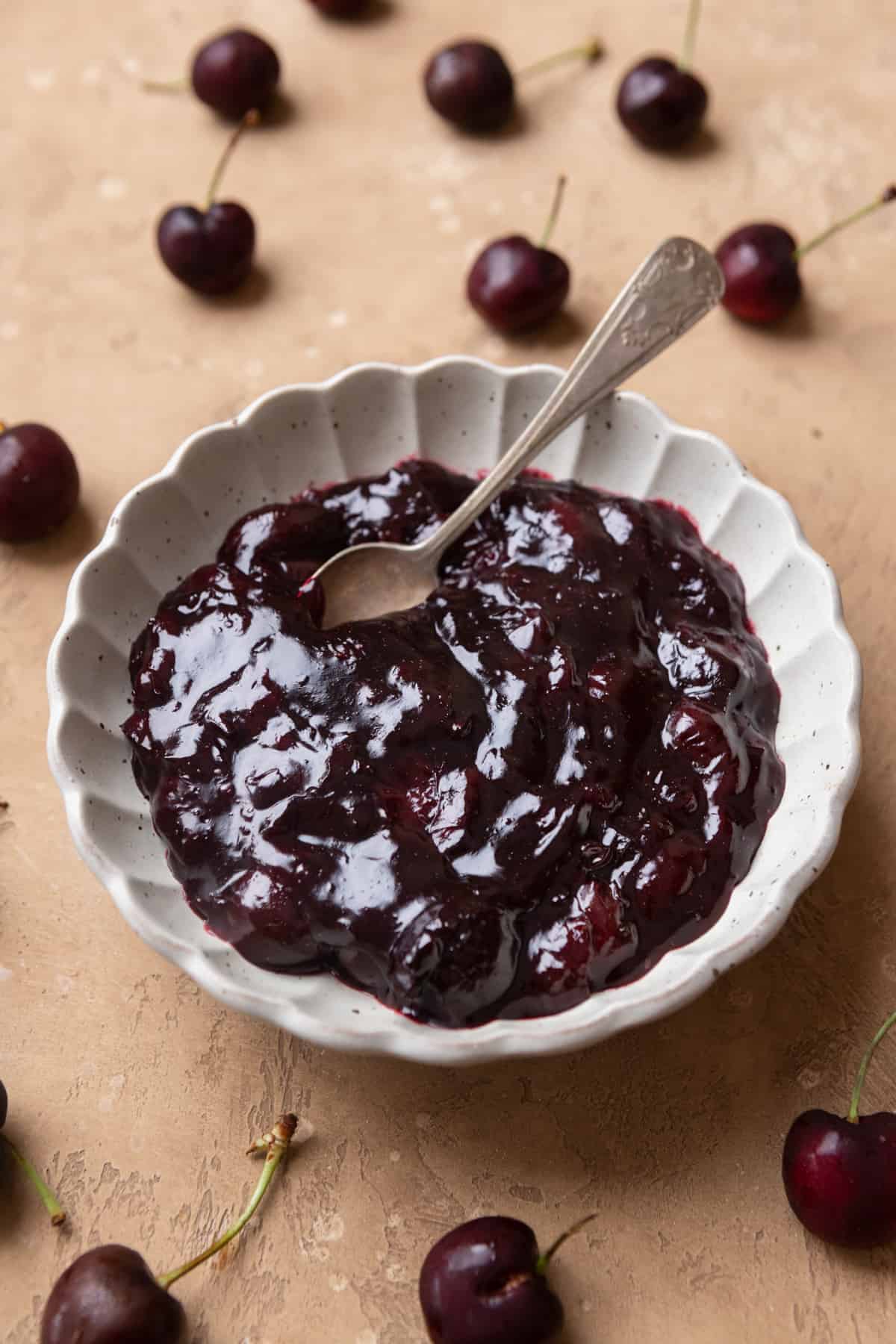 Cherry filling in a scalloped white bowl with a spoon.
