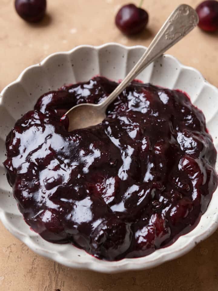 Cherry cake filling in a white bowl with a spoon.