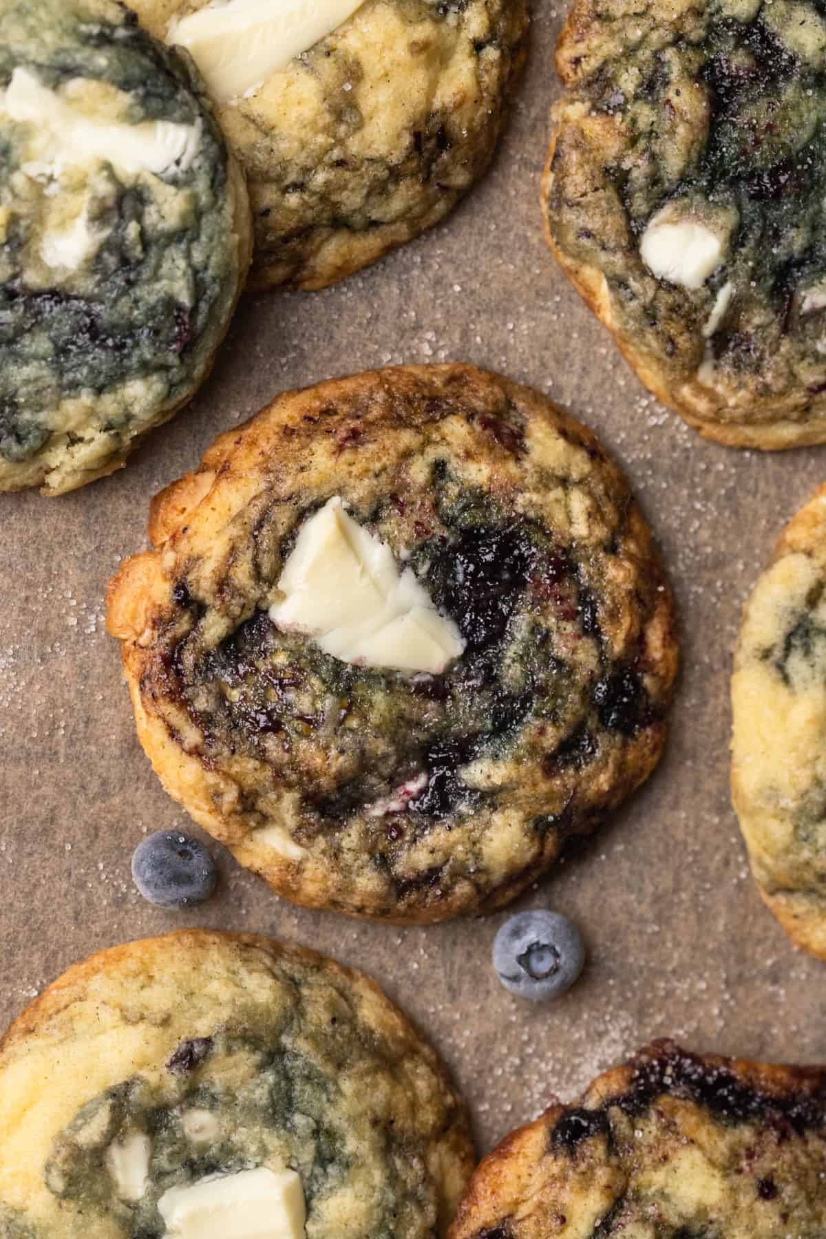 Cookies on tan parchment paper with blueberries.