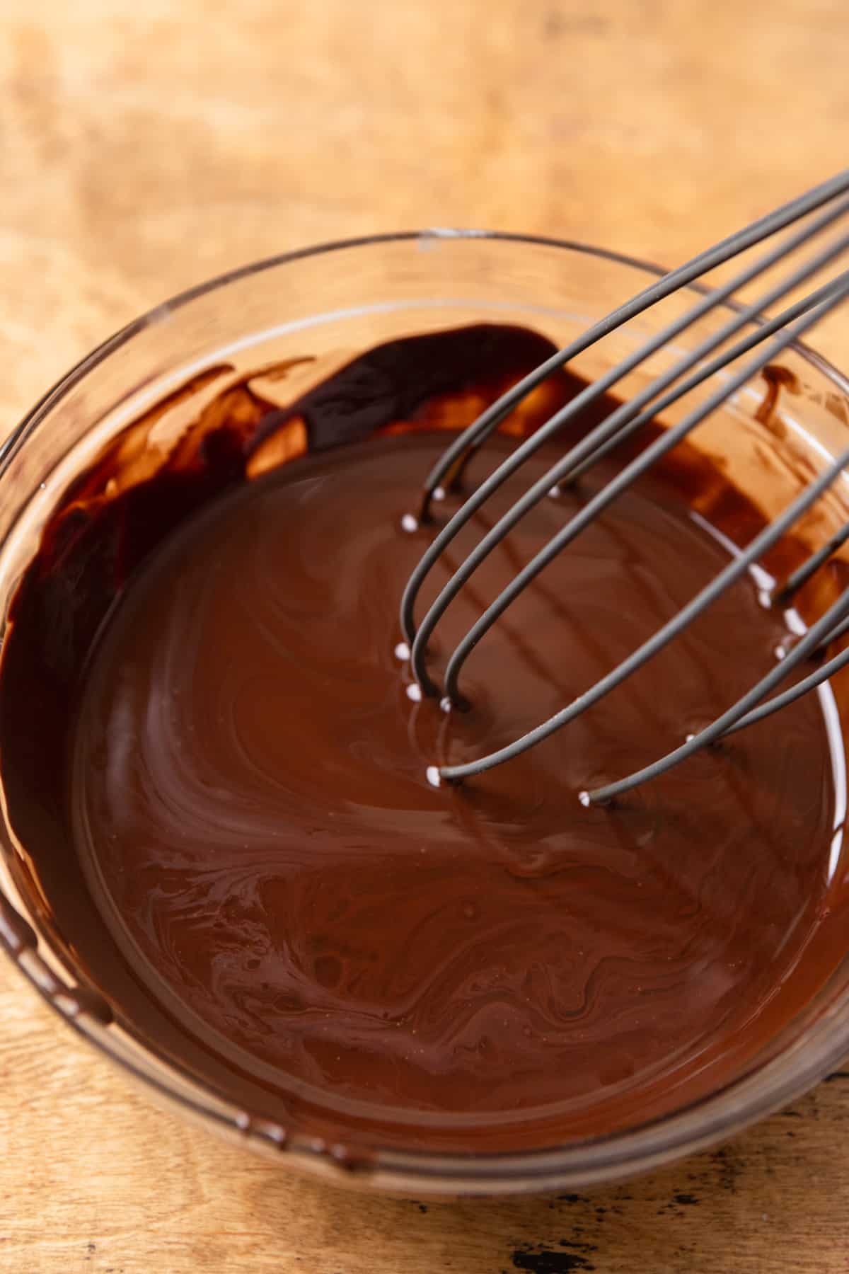 Melted chocolate and oil in a bowl with a whisk.