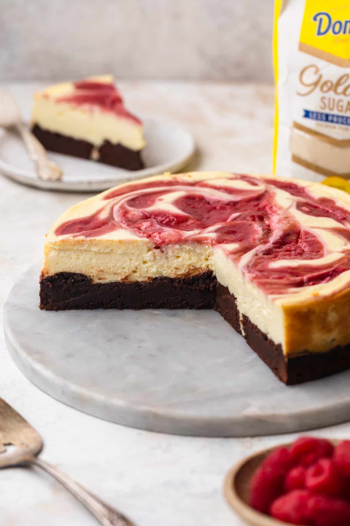 Raspberry brownie cheesecake on a white platter.