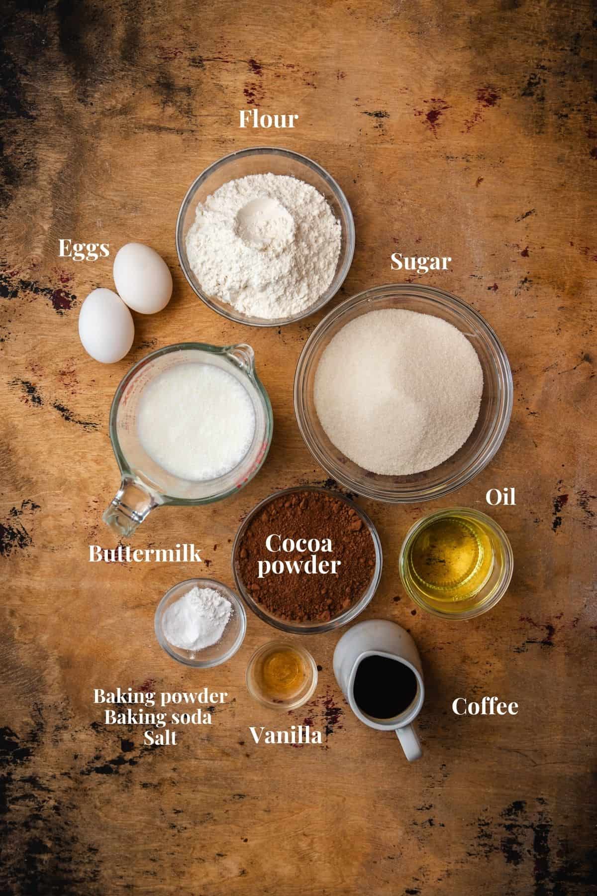 Ingredients to make chocolate cake on a wood surface.
